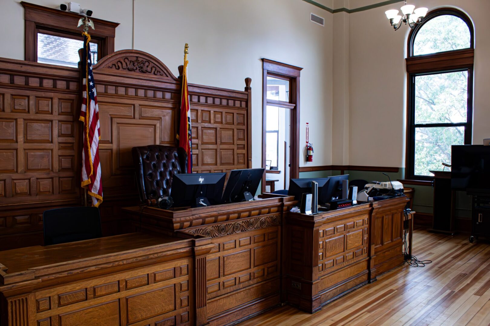 A courtroom with wooden benches and flags on the walls.